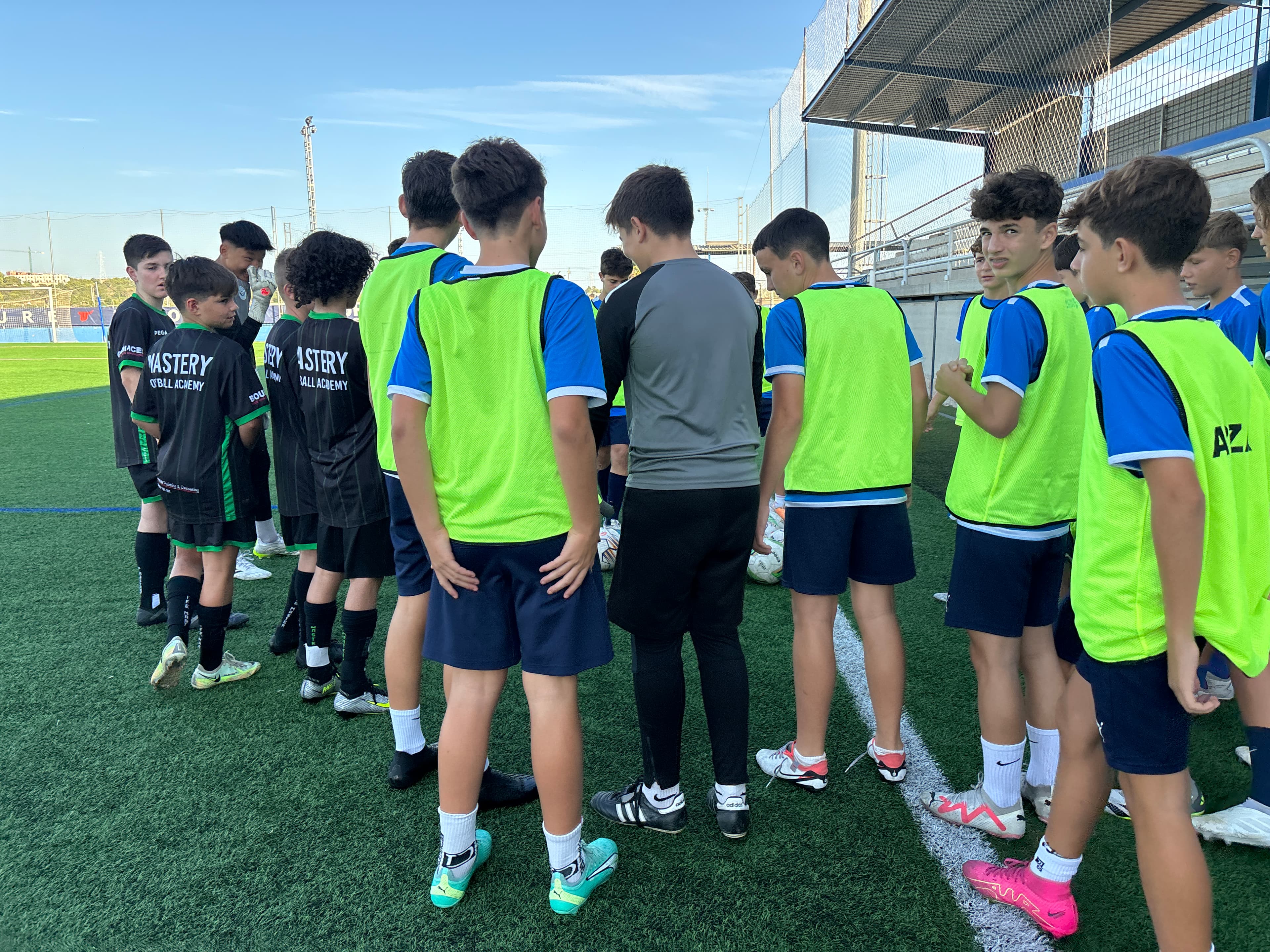 Mastery Football Academy players in black kit training alongside Spanish academy players in bibs at CF Cracks during the Spain Pathway tour